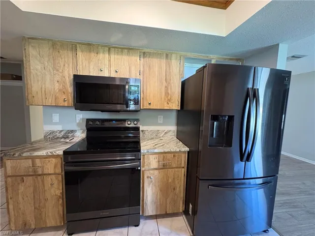 Kitchen featuring a textured ceiling and appliances with stainless steel finishes