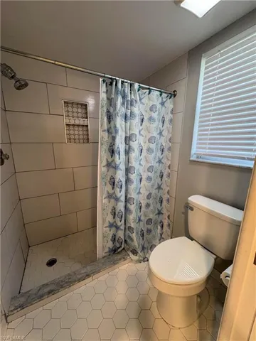 Bathroom with tile patterned flooring, toilet, and a shower with shower curtain