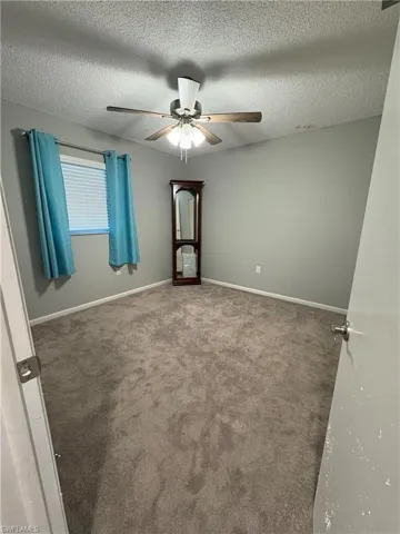 Carpeted spare room with ceiling fan and a textured ceiling