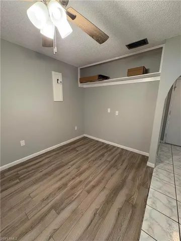 Empty room with hardwood / wood-style flooring, ceiling fan, and a textured ceiling