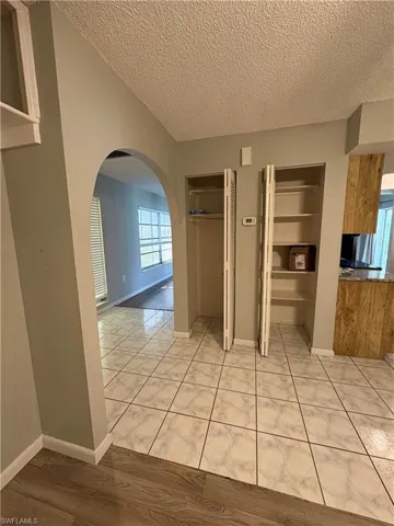 Hall with light tile patterned flooring, built in features, and a textured ceiling