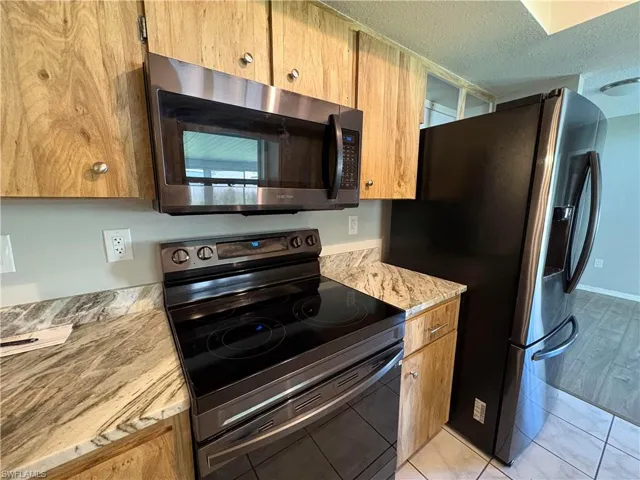 Kitchen featuring a textured ceiling, stainless steel appliances, and light tile patterned floors
