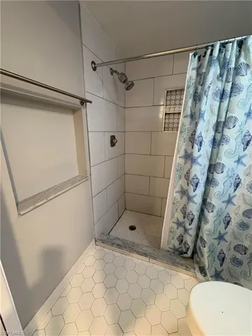 Bathroom with tile patterned floors, toilet, and curtained shower