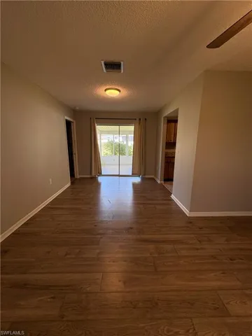 Unfurnished room featuring ceiling fan, dark hardwood / wood-style floors, and a textured ceiling