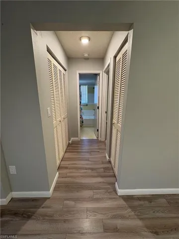 Hallway with a textured ceiling and light hardwood / wood-style floors
