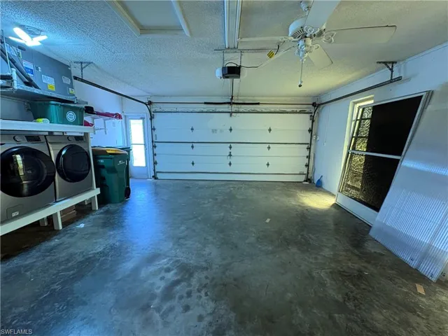 Garage featuring ceiling fan, a garage door opener, and independent washer and dryer