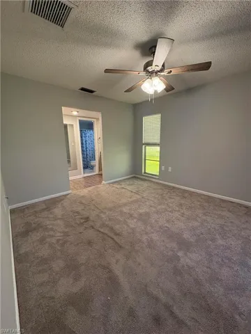 Empty room featuring ceiling fan, a textured ceiling, and carpet