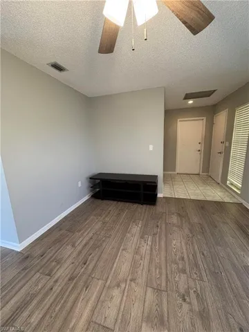 Empty room featuring ceiling fan, light hardwood / wood-style floors, and a textured ceiling