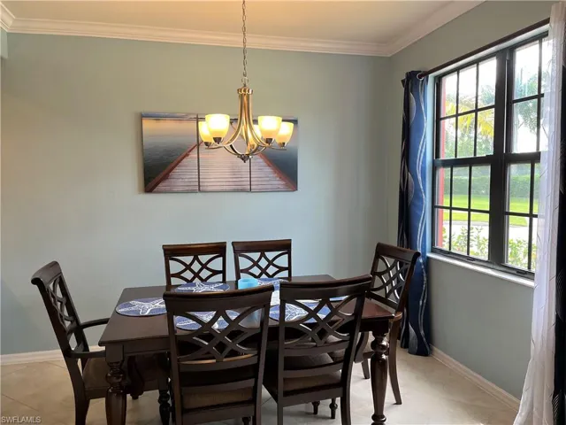 Dining area with a chandelier, crown molding, light tile patterned floors, and baseboards