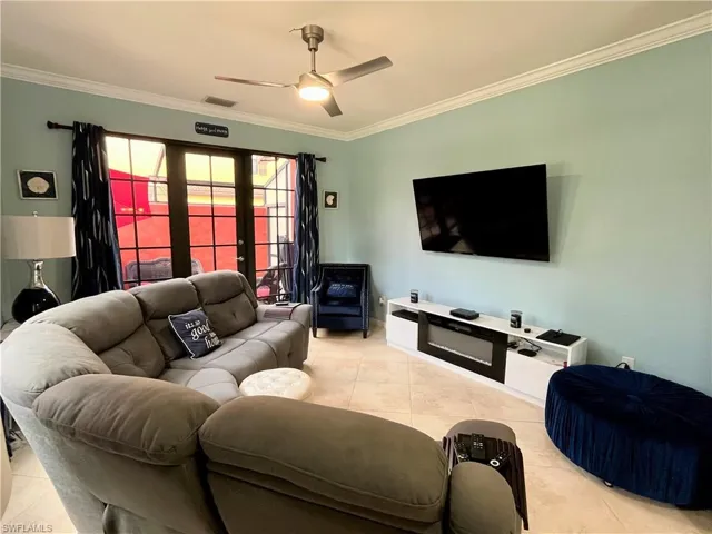 Living area featuring a ceiling fan, visible vents, ornamental molding, and tile patterned flooring