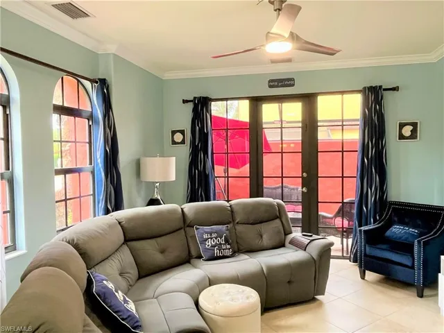 Living area with light tile patterned floors, french doors, a ceiling fan, crown molding, and visible vents