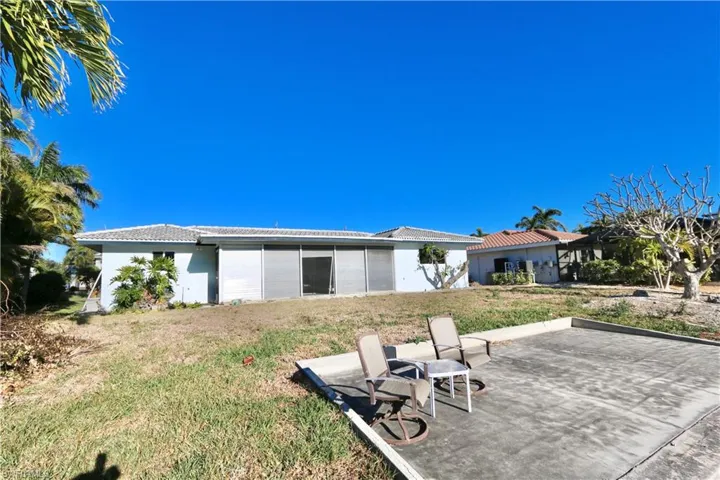Rear view of property with a lawn, stucco siding, a tile roof, and a patio