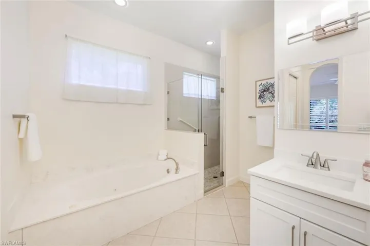 Soaking tub & shower with frameless shower door and newly tiled.