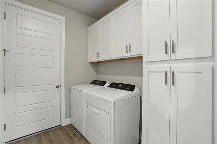Laundry area with cabinet space, washer and dryer, dark wood-type flooring, and baseboards