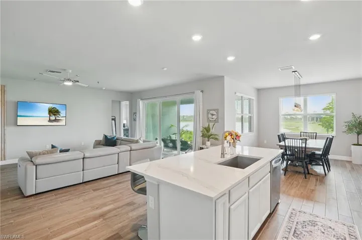 Kitchen featuring a sink, open floor plan, light wood-type flooring, an island with sink, and healthy amount of natural light