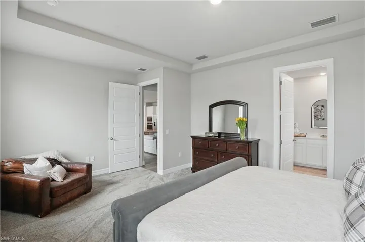 Carpeted bedroom featuring baseboards, recessed lighting, and ensuite bathroom