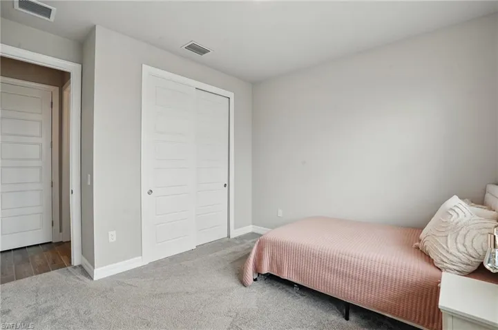 Carpeted bedroom featuring a closet and baseboards