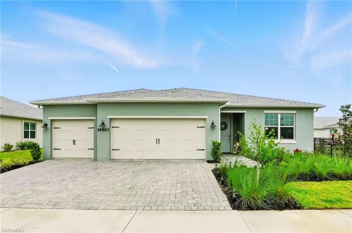 View of front of house with decorative driveway, a garage, and stucco siding