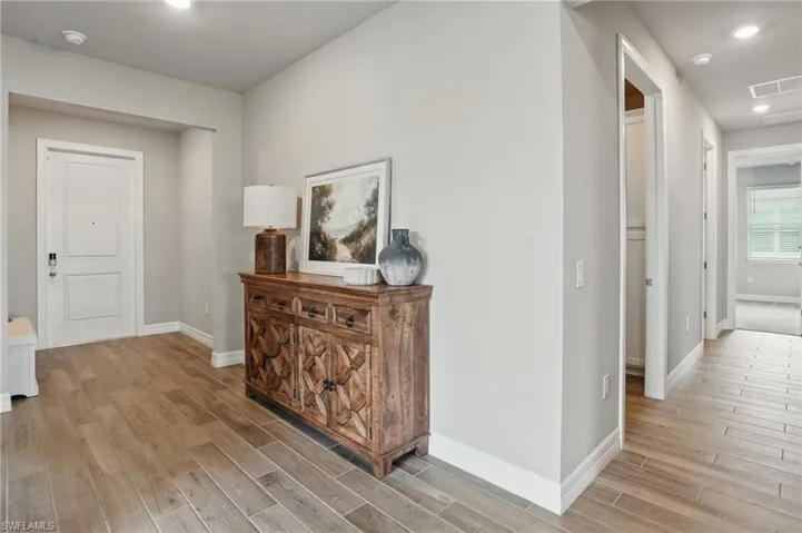 Hall featuring light wood-type flooring, baseboards, and recessed lighting
