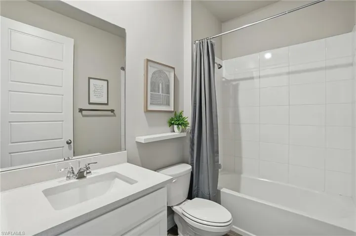 Full bathroom with toilet, vanity, and shower / bath combo with shower curtain