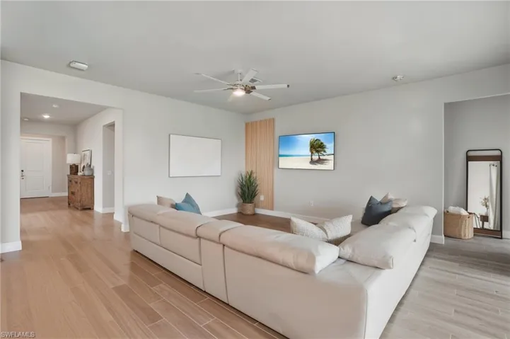 Living area with light wood-style flooring, baseboards, ceiling fan, and recessed lighting