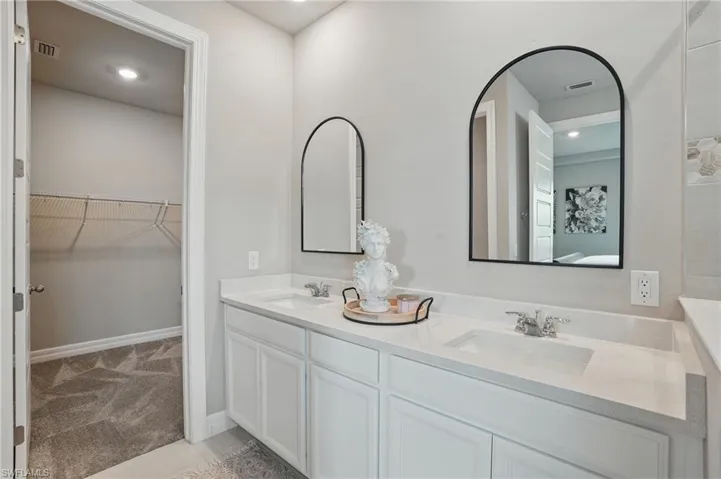 Full bath with double vanity, a walk in closet, and recessed lighting