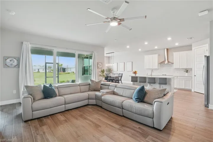 Living room with light wood-type flooring, ceiling fan, recessed lighting, and baseboards