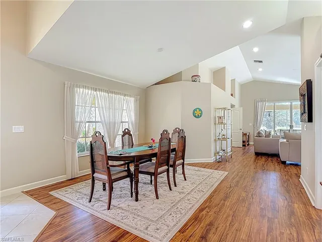 Dining space with lofted ceiling, laminate floors, and recessed lighting