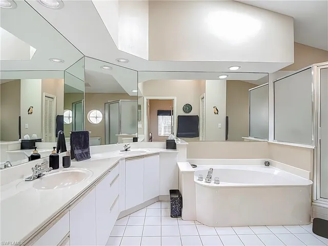 Bathroom featuring double vanity, a bath, a shower stall, light tile patterned floors, and recessed lighting