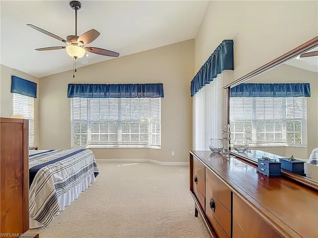 Primary Bedroom with lofted ceiling, light carpet, and ceiling fan