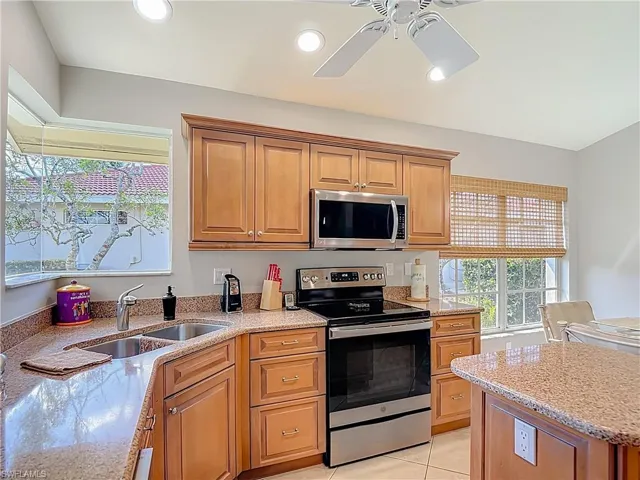 Kitchen featuring stainless steel appliances, light stone counters, a ceiling fan, wood finish cabinetry, and recessed lighting