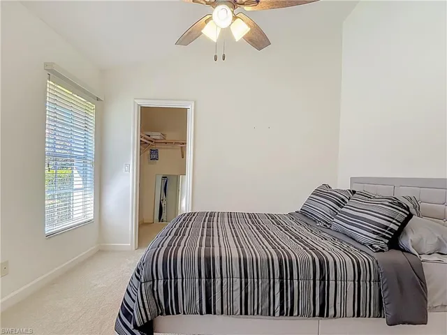 Bedroom featuring light carpet, vaulted ceiling, a spacious closet, and a ceiling fan