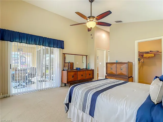 Primary Bedroom with carpet flooring, a spacious closet, vaulted ceiling, access to outside, and a ceiling fan