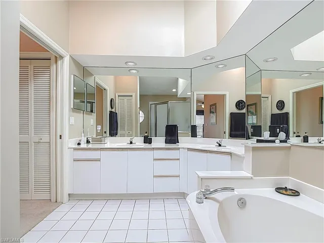 Bathroom featuring vanity, a stall shower, a closet, a bath, and light tile patterned flooring