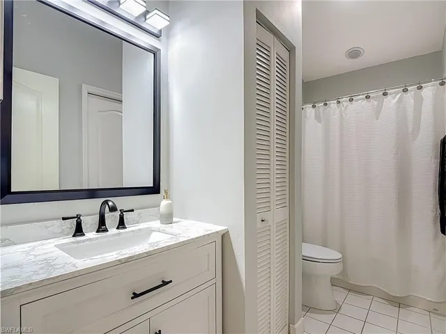 Bathroom with a closet, vanity, and light tile patterned flooring