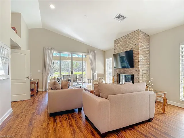 Living room with laminate floors, a fireplace, and lofted ceiling