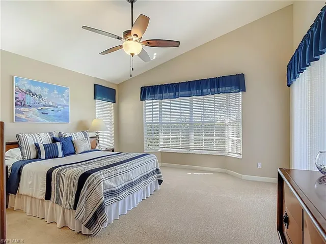 Primary Bedroom featuring vaulted ceiling, light carpet, and a ceiling fan