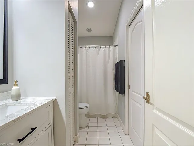 Full bathroom with a closet, vanity, light tile patterned floors, and a shower/tub combo with curtain