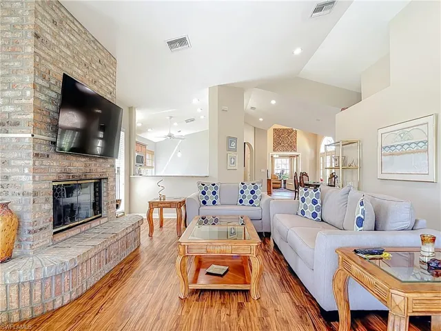 Living area with a fireplace, laminate floors, vaulted ceiling, recessed lighting