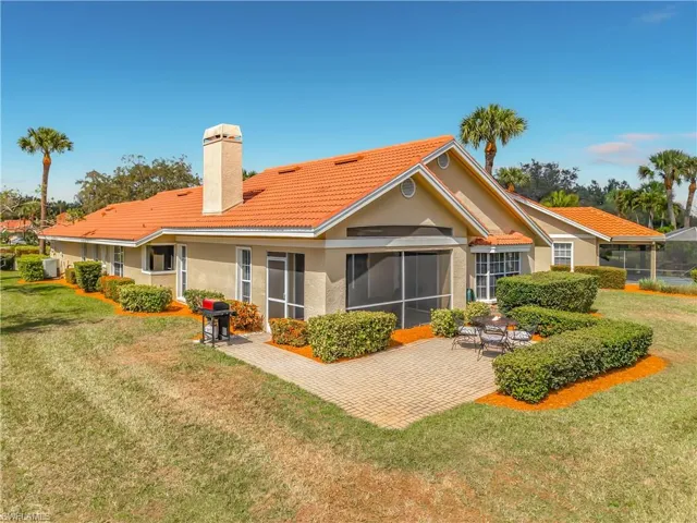 Back of house with a screened in lanai, outdoor patio, a tile roof, stucco siding, a yard, and a chimney