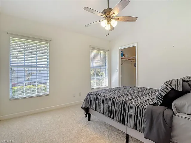 Carpeted bedroom with vaulted ceiling and a ceiling fan