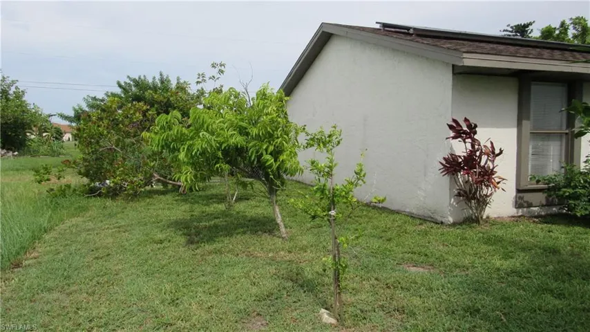 View of side of property featuring stucco siding and a yard