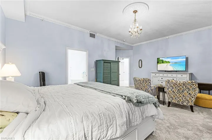 Bedroom featuring carpet floors, crown molding, and a chandelier