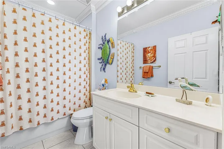 Bathroom featuring vanity, ornamental molding, shower / tub combo, and light tile patterned floors