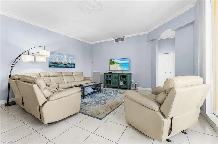 Living room with crown molding and arched walkways