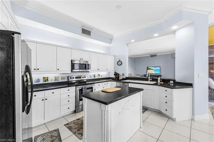 Kitchen featuring stainless steel appliances, ornamental molding, recessed lighting, white cabinets, and dark countertops