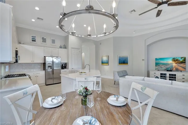 Dining room with arched walkways, crown molding, light tile patterned floors, a ceiling fan, and recessed lighting