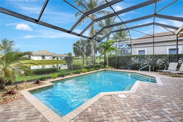 Swimming pool with glass enclosure, a water view, a patio, and a sunroom