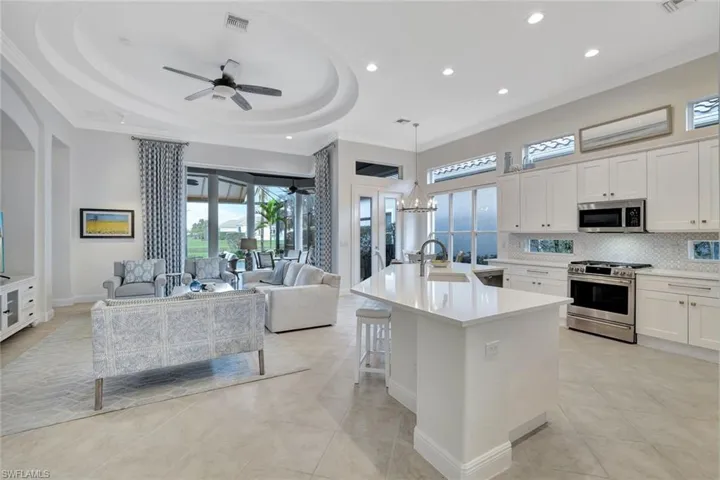 Kitchen with tasteful backsplash, white cabinetry, appliances with stainless steel finishes, a ceiling fan, and hanging light fixtures