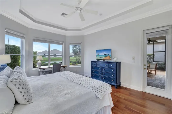 Bedroom featuring a raised ceiling, wood finished floors, ornamental molding, and ceiling fan